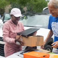 Volunteer helping new arrival pack items into moving bin